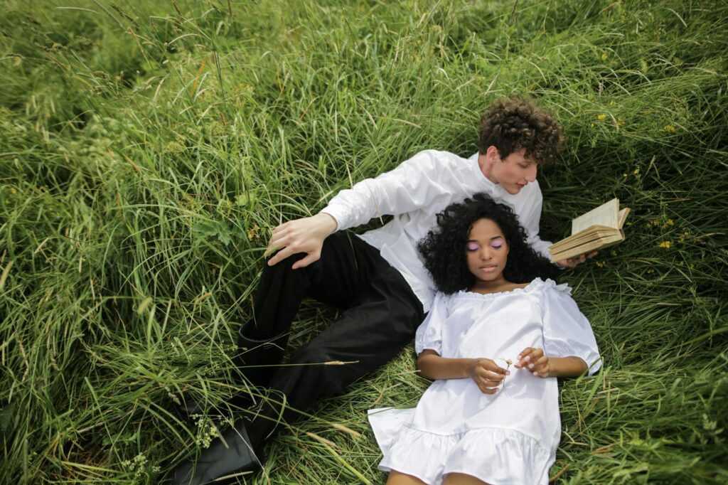 man in white dress shirt lying on green grass field