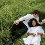 man in white dress shirt lying on green grass field