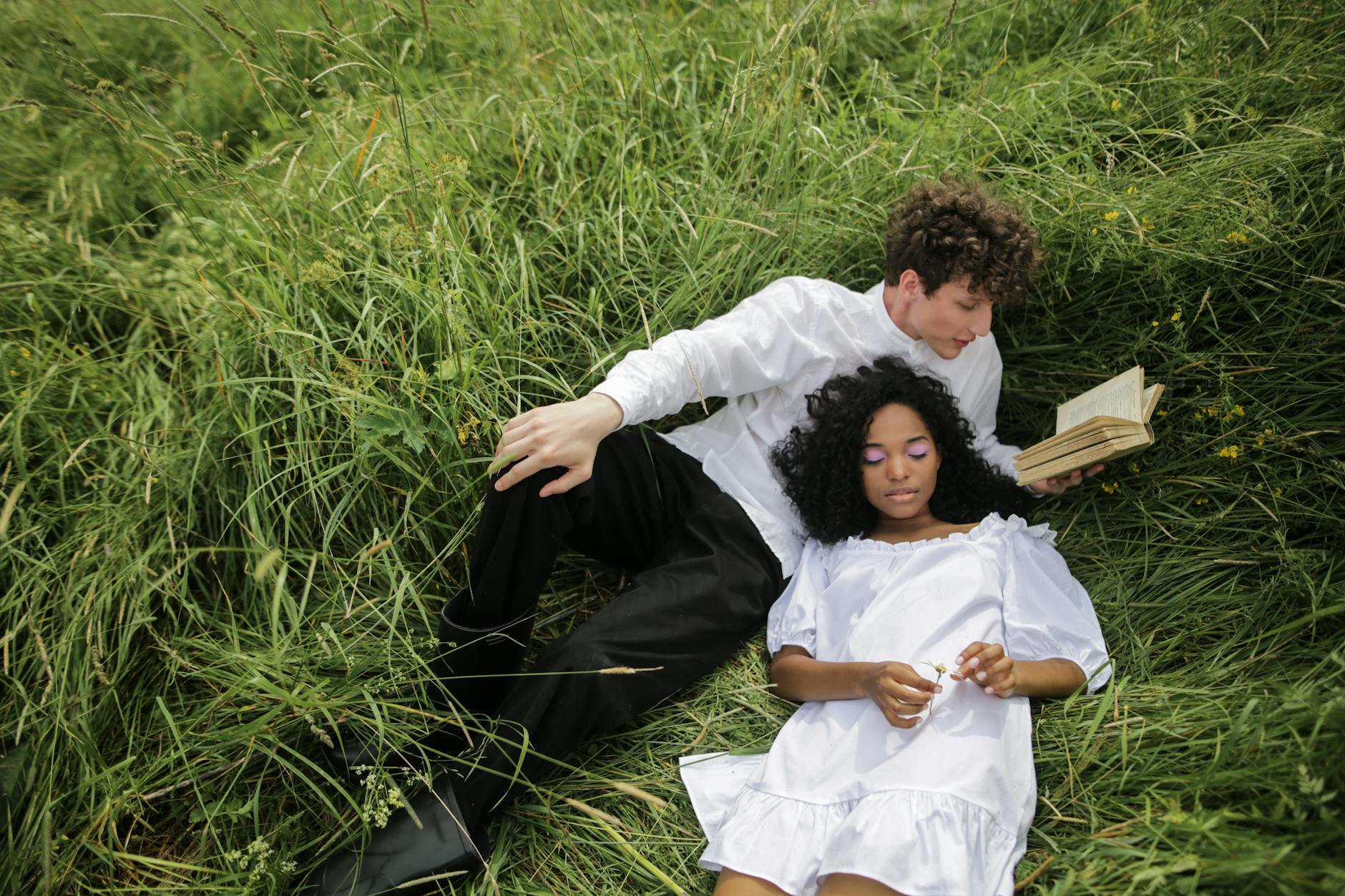 man in white dress shirt lying on green grass field