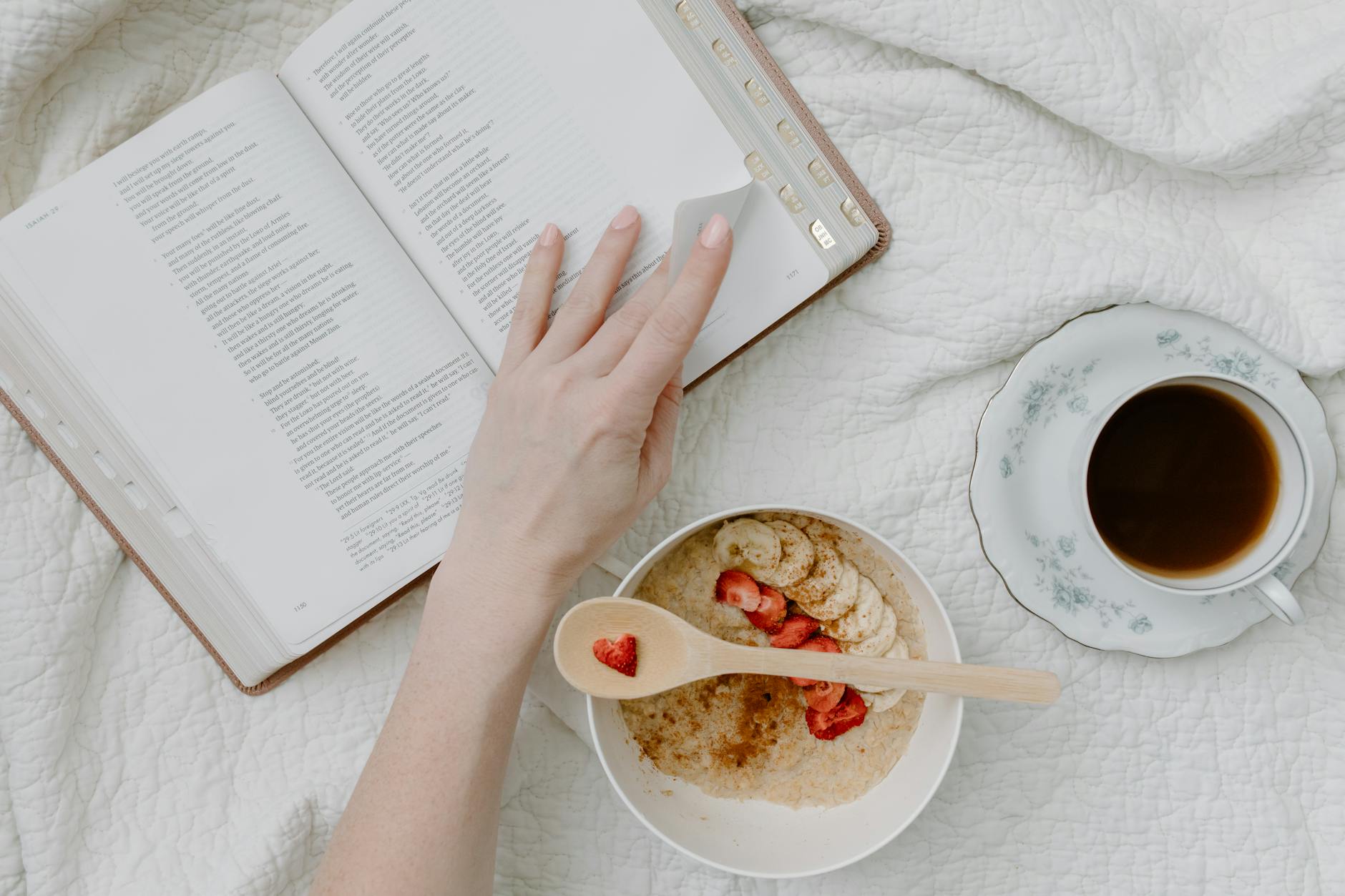 a person having breakfast while reading a book